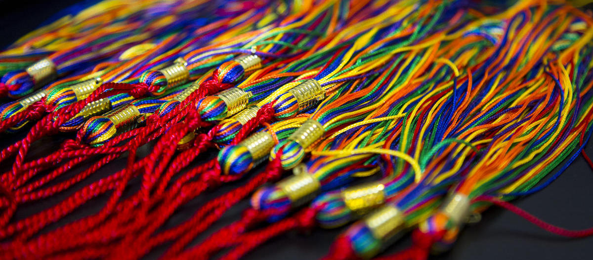 A close up image of a many rainbow colored graduation tassels.