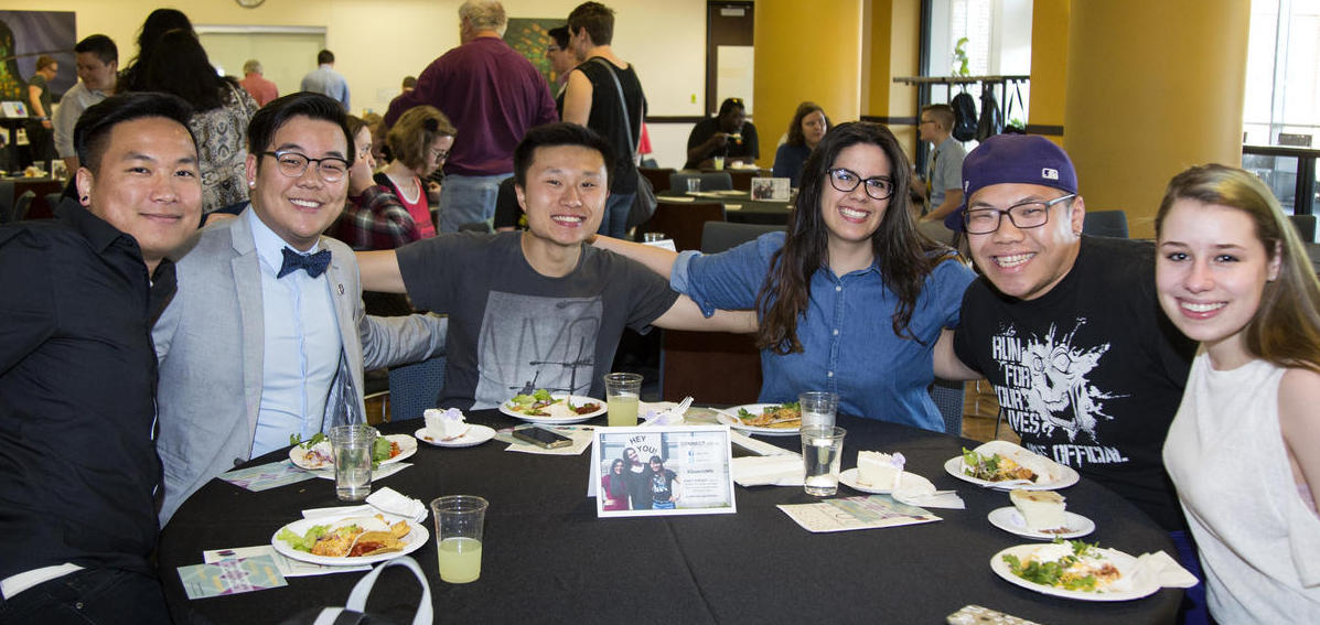 Photo of 6 students sitting at a table smiling for the camera